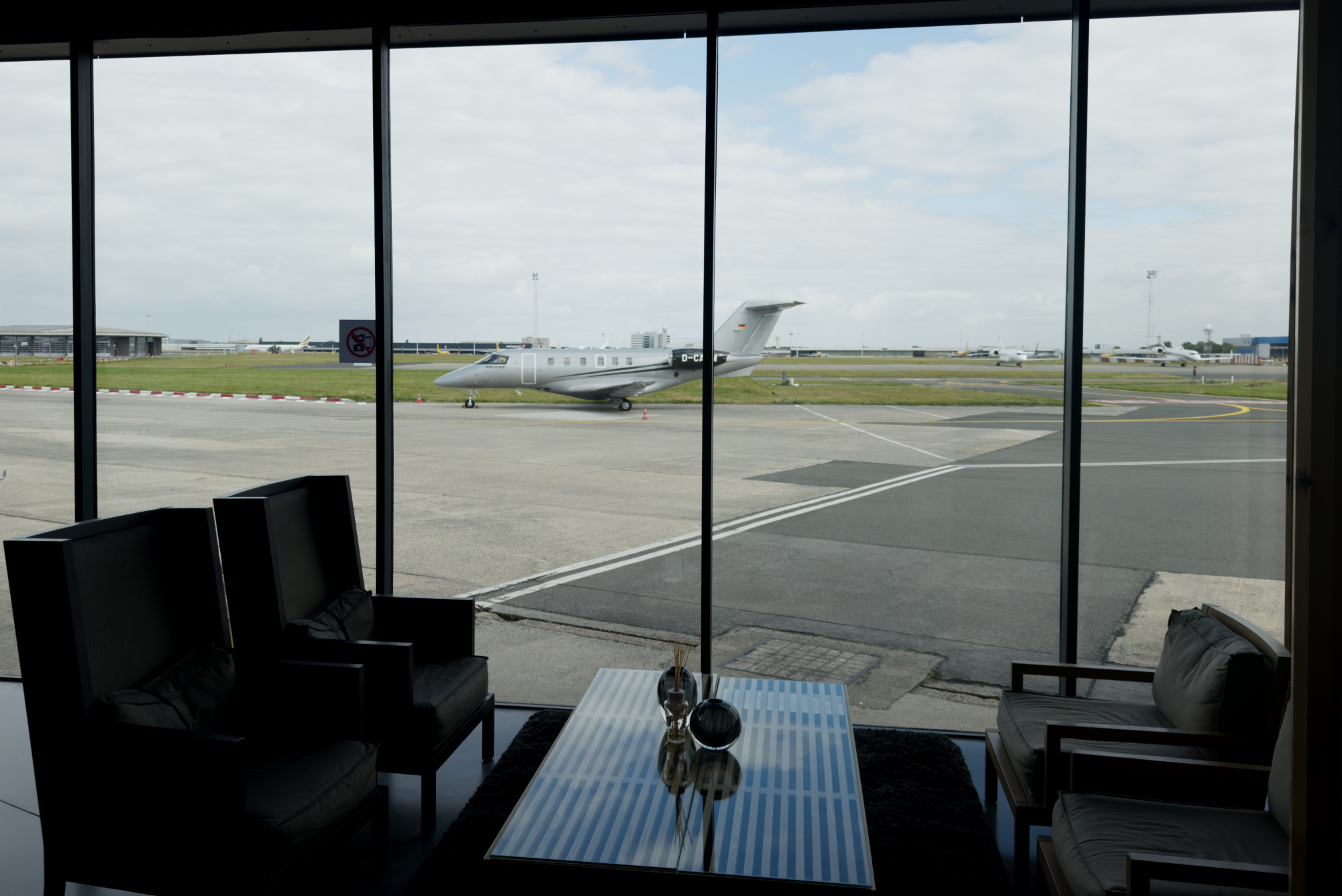 Airport lounge view of a private Pilatus jet parked on the tarmac