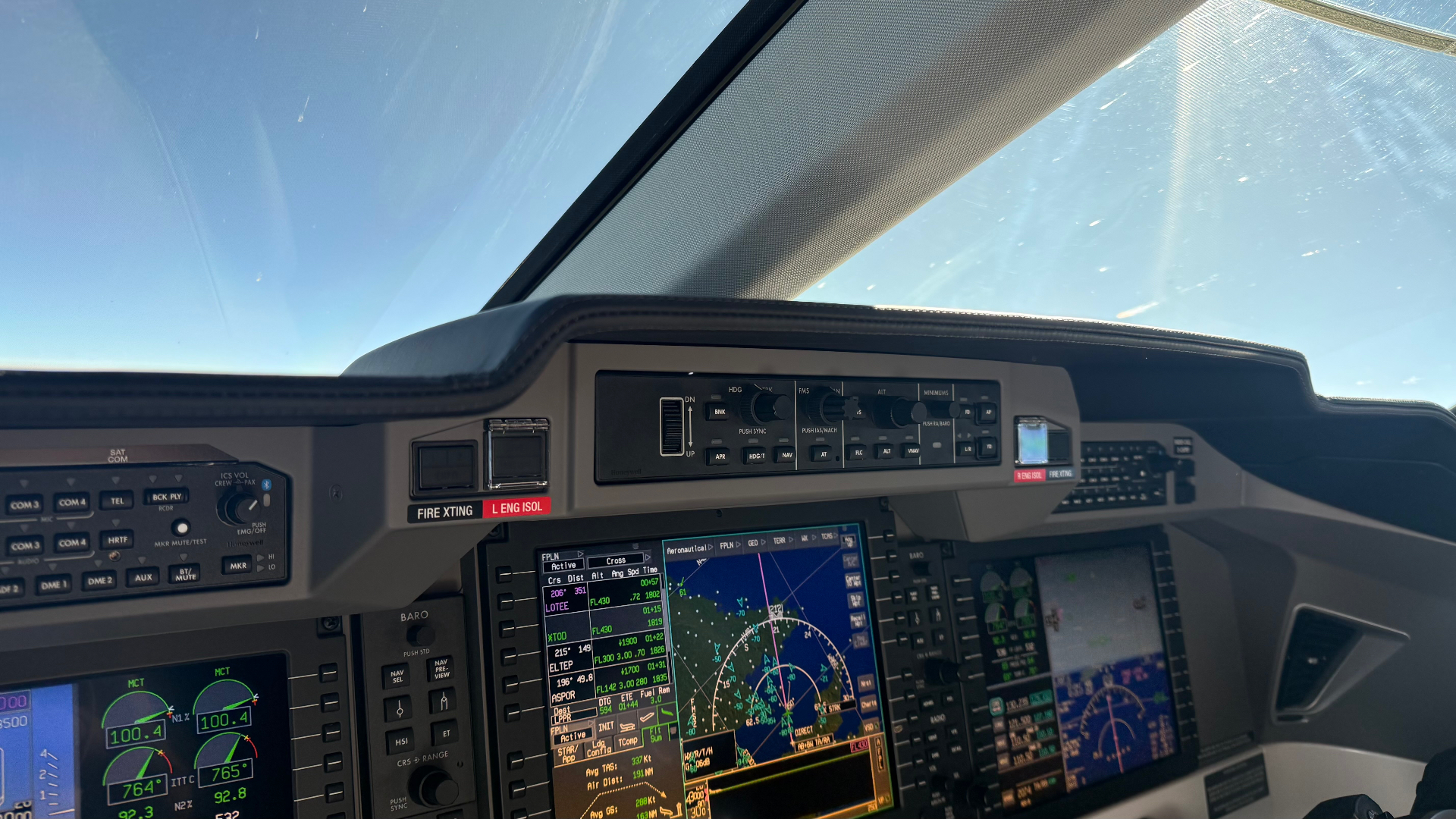 Business jet cockpit in flight, looking out at clear blue sky